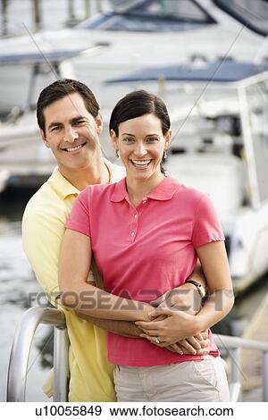 Portrait of Caucasian mid-adult couple embracing at harbor. View Large Photo Image Stock Photo - Portrait of Caucasian mid-adult couple embracing at harbor. . Fotosearch