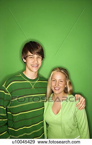 Portrait of Caucasian teen boy and girl standing against green background smiling with arms around eachother. View Large Photo Image Stock Photo - Portrait of Caucasian teen boy and girl standing against green background smiling with arms around eachother. . Fotosearch