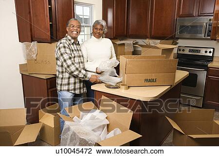 Portrait of middle-aged African-American couple packing moving boxes in kitchen. View Large Photo Image Stock Image - Portrait of middle-aged African-American couple packing moving boxes in kitchen.. Fotosearch
