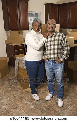 Stock Photography - Portrait of middle-aged African-American couple in kitchen with moving boxes.. Fotosearch