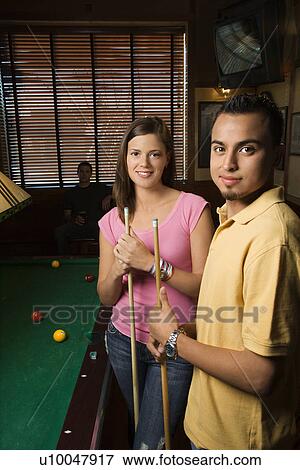 Stock Photo - Portrait of young man and woman playing billiards.. Fotosearch