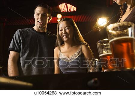Stock Photo - Young couple teamed up at foosball game in pub.. Fotosearch
