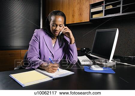 African-American young adult business woman talking on cell phone and writing in planner in office. View Large Photo Image Stock Photo - African-American young adult business woman talking on cell phone and writing in planner in office.. Fotosearch