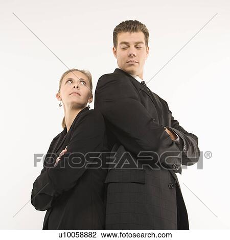 Stock Image - Caucasian mid-adult businessman and woman standing back to back looking at each other. . Fotosearch