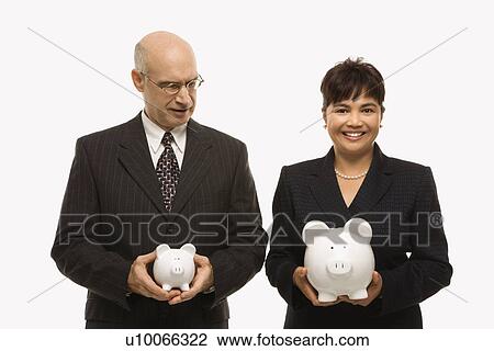 Stock Image - Caucasian middle-aged businessman and Filipino businesswoman holding different sized piggybanks.. Fotosearch