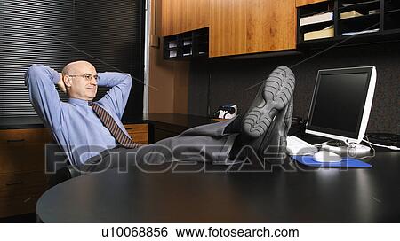 Caucasian middle-aged businessman in office sitting with feet on desk. View Large Photo Image Stock Photograph - Caucasian middle-aged businessman in office sitting with feet on desk.. Fotosearch