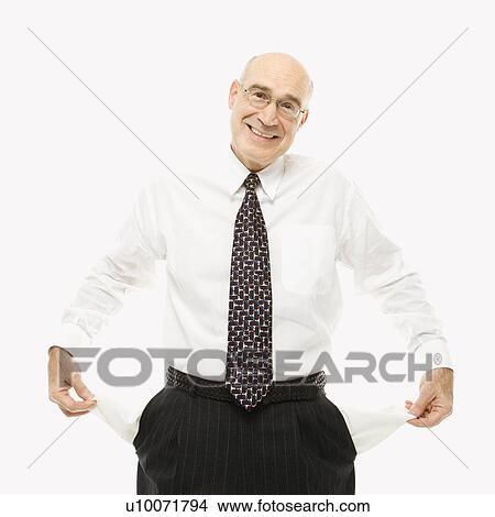 Picture - Caucasian middle-aged businessman pulling empty pockets out standing against white background.. Fotosearch
