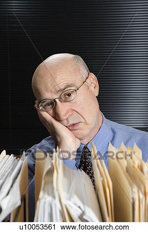 Caucasian middle-aged businessman with files leaning head on hand looking tired. View Large Photo Image Stock Image - Caucasian middle-aged businessman with files leaning head on hand looking tired.. Fotosearch