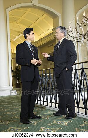 Caucasian prime adult male businessman and Asian prime adult male businessman in hotel. View Large Photo Image Picture - Caucasian prime adult male businessman and Asian prime adult male businessman in hotel.. Fotosearch