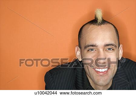 Head and shoulder portrait of Caucasian man in suit with mohawk smiling against orange background. View Large Photo Image Picture - Head and shoulder portrait of Caucasian man in suit with mohawk smiling against orange background.. Fotosearch