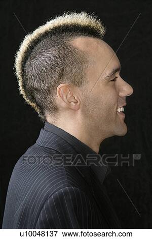 Stock Photo - Portrait of Caucasian man in suit with mohawk against black background.. Fotosearch