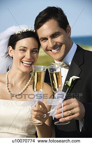 Caucasian mid-adult bride and groom toasting champagne looking at viewer and smiling. View Large Photo Image Picture - Caucasian mid-adult bride and groom toasting champagne looking at viewer and smiling.. Fotosearch