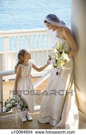 Picture - Caucasian mid-adult bride holding hands with flower girl.. Fotosearch