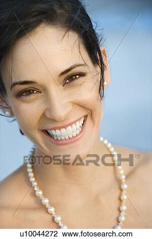 Stock Image - Portait of Caucasian mid-adult woman in pearls smiling and looking at viewer.. Fotosearch