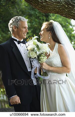 Picture - Portrait of a bride and groom smiling at each other outside.. Fotosearch