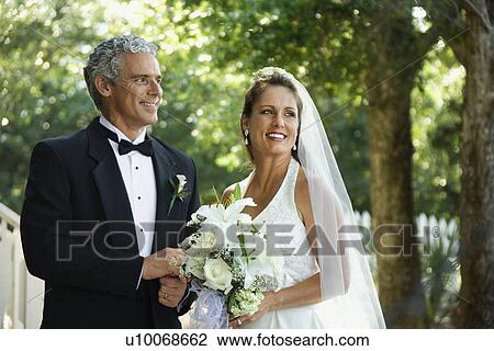 Stock Image - Portrait of bride and groom holding hands outside.. Fotosearch