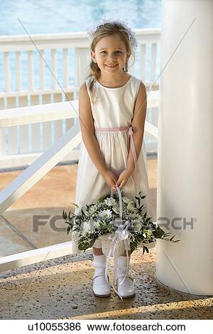 Stock Photograph - Portrait of Caucasian flower girl holding flower basket smiling.. Fotosearch