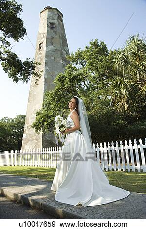 Stock Photo - Portrait of mid-adult bride with lighthouse in background.. Fotosearch