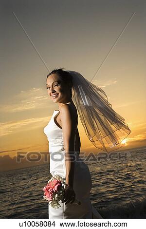Young adult female Caucasian bride holding bouquet on beach. View Large Photo Image Picture - Young adult female Caucasian bride holding bouquet on beach.. Fotosearch