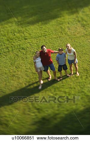 Caucasian family of four standing on lawn with arms around each other. View Large Photo Image Stock Image - Caucasian family of four standing on lawn with arms around each other.. Fotosearch