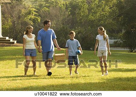 Caucasian family of four walking in park carrying picnic basket. View Large Photo Image Stock Image - Caucasian family of four walking in park carrying picnic basket.. Fotosearch