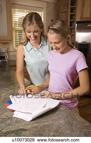 Caucasian mid-adult mother helping pre-teen daughter with homework at kitchen counter. View Large Photo Image Stock Photo - Caucasian mid-adult mother helping pre-teen daughter with homework at kitchen counter.. Fotosearch