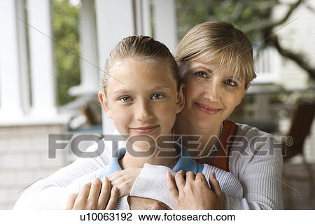 Stock Image - Caucasian mid-adult mother hugging pre-teen daughter.. Fotosearch
