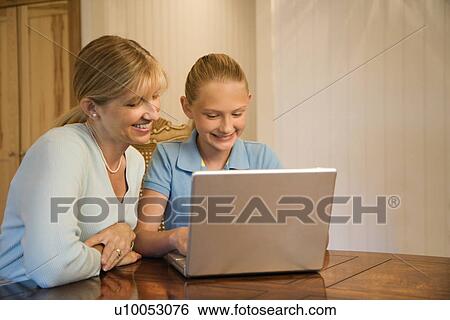 Stock Photograph - Caucasian mid-adult woman and pre-teen girl using laptop computer.. Fotosearch
