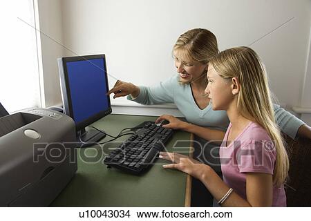 Picture - Caucasian pre-teen girl and Caucasian prime mid-adult woman working on computer together.. Fotosearch