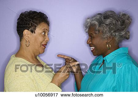 Stock Photo - Mature adult African American females pointing at eachother.. Fotosearch