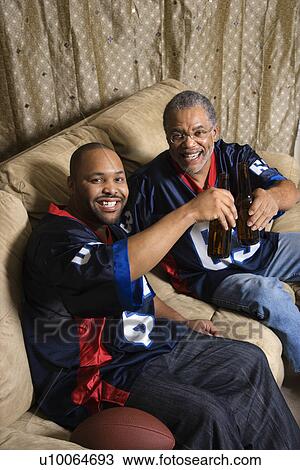 Portrait of an African-American father and son toasting with beer on couch. View Large Photo Image Stock Image - Portrait of an African-American father and son toasting with beer on couch.. Fotosearch