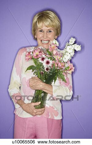 Stock Photograph - Caucasian mature adult female holding flower bouquet.. Fotosearch