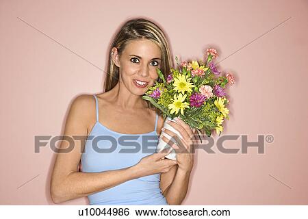 Stock Photograph - Caucasian mid-adult female holding pot of flowers.. Fotosearch