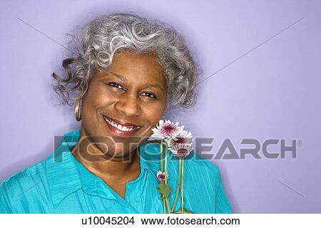 Mature adult African American female holding flowers smiling. View Large Photo Image Picture - Mature adult African American female holding flowers smiling.. Fotosearch