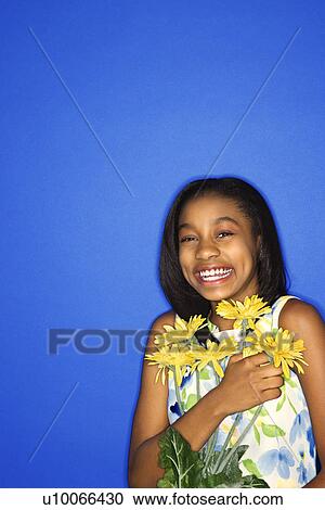 Portrait of African-American teen girl holding a bouquet of daisies and smiling against blue background. View Large Photo Image Stock Image - Portrait of African-American teen girl holding a bouquet of daisies and smiling against blue background.. Fotosearch