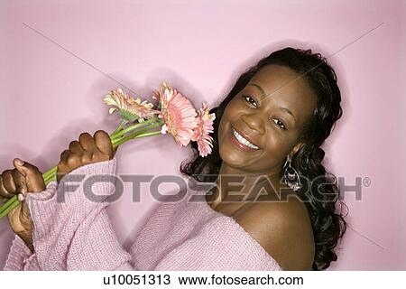 Portrait of smiling African-American mid-adult woman on pink background holding pink flowers. View Large Photo Image Stock Image - Portrait of smiling African-American mid-adult woman on pink background holding pink flowers.. Fotosearch