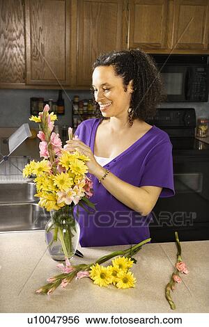 Stock Photograph - Portrait of young pregnant mother arranging flowers.. Fotosearch