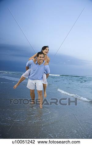 Caucasian mid-adult male carrying female piggyback style on beach. View Large Photo Image Stock Image - Caucasian mid-adult male carrying female piggyback style on beach.. Fotosearch