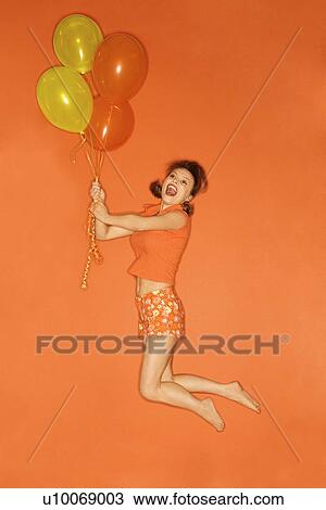 Caucasian mid-adult woman being lifted into the air by balloons, on orange background. View Large Photo Image Stock Image - Caucasian mid-adult woman being lifted into the air by balloons, on orange background.. Fotosearch
