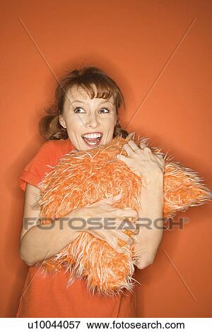 Caucasian mid-adult woman on orange background hugging fuzzy orange pillow. View Large Photo Image Stock Photo - Caucasian mid-adult woman on orange background hugging fuzzy orange pillow.. Fotosearch