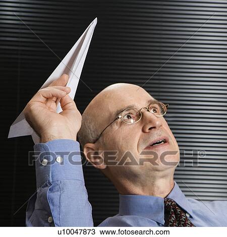 Stock Image - Caucasian middle-aged businessman playing with paper airplane.. Fotosearch