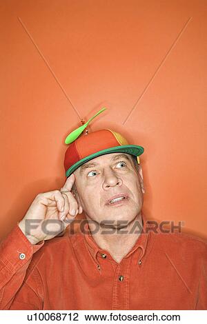Contemplative niddle-aged Caucasian man wearing propeller cap on orange background. View Large Photo Image Stock Image - Contemplative niddle-aged Caucasian man wearing propeller cap on orange background.. Fotosearch