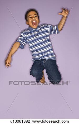 Stock Image - Portrait of young boy jumping.. Fotosearch