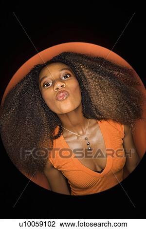 Vignette of young African-American adult woman with big hair and low cut dress on orange background puckering her lips. View Large Photo Image Stock Image - Vignette of young African-American adult woman with big hair and low cut dress on orange background puckering her lips.. Fotosearch