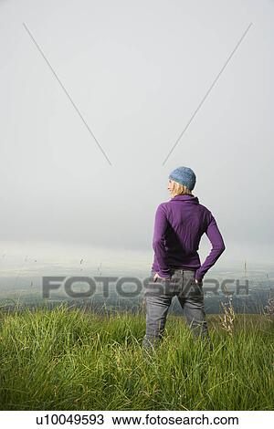 Back view of smiling middle-aged Caucasian woman standing alone in field looking to side. View Large Photo Image Stock Image - Back view of smiling middle-aged Caucasian woman standing alone in field looking to side.. Fotosearch