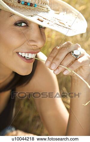 Close-up of mid-adult Caucasian woman wearing straw cowboy hat and chewing on blade of grass. View Large Photo Image Stock Photo - Close-up of mid-adult Caucasian woman wearing straw cowboy hat and chewing on blade of grass.. Fotosearch