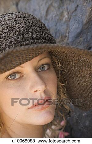 Stock Photo - Close-up of young adult female Caucasian by rock wearing brimmed hat.. Fotosearch