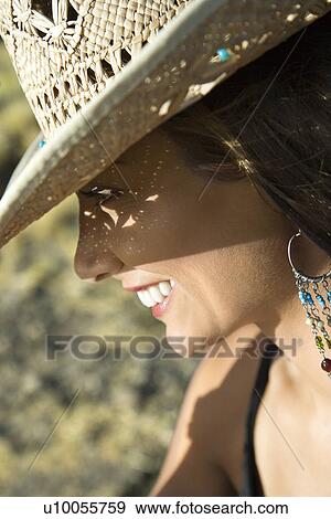 Stock Photo - Close-up profile of smiling young mid-adult Caucasian woman wearing straw cowboy hat.. Fotosearch