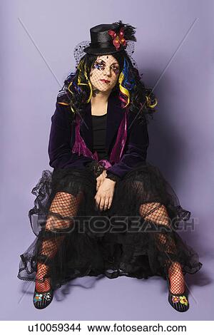Portrait of Caucasian woman with unique hat, hair and attire sitting against purple background. View Large Photo Image Picture - Portrait of Caucasian woman with unique hat, hair and attire sitting against purple background.. Fotosearch