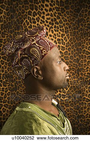 Stock Image - Side view portrait of African-American mid-adult man wearing traditional African clothing.. Fotosearch